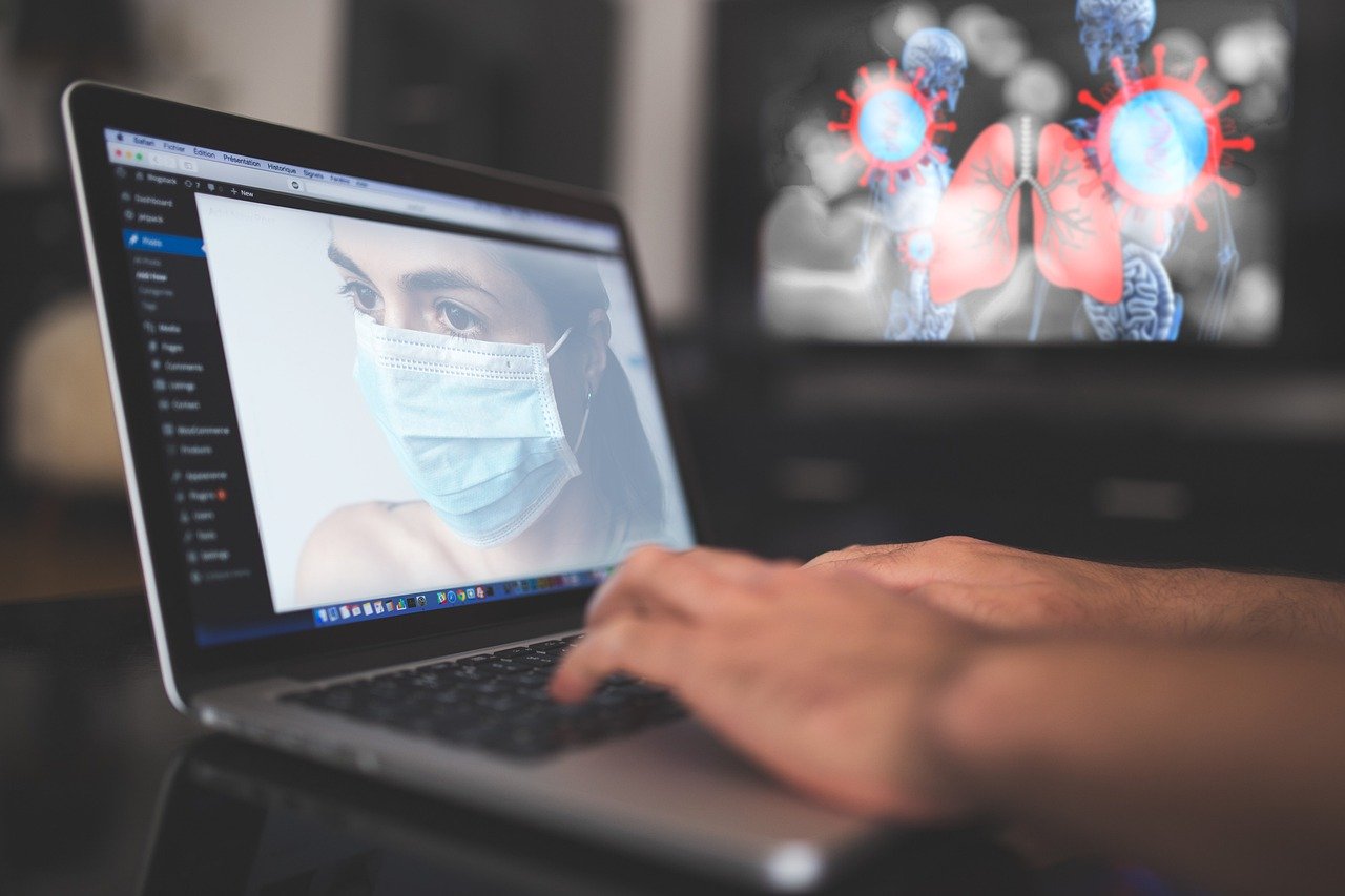 Laptop mit Bild einer Person mit Mundschutz. Im Hintergrund eine stilisierte Lunge.